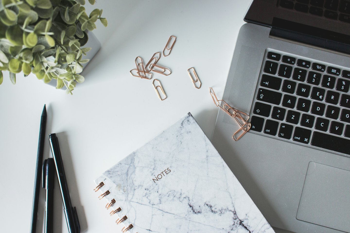 Minimalist desk setup with a laptop, notebook, and stationery items.